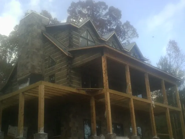 Stone chimney and dormers on a large log home with a timber porch in Shelby